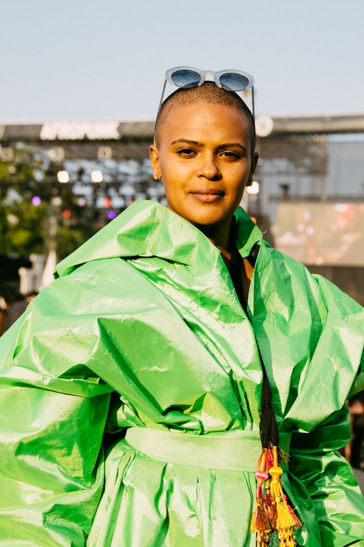 A woman in a green trench coat, with a buzz cut and sunglasses on her head at the Afropunk festival 