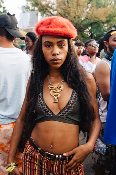 A woman in a black bikini top, striped pants, a dragon necklace and an orange beret at the Afropunk ...