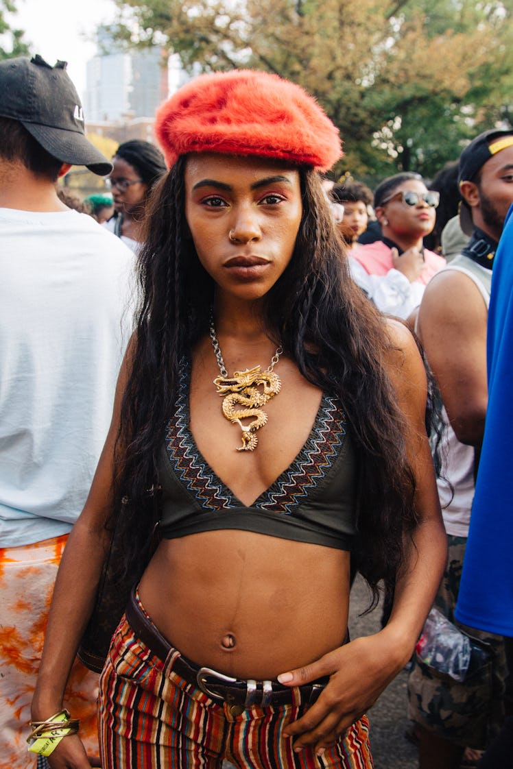 A woman in a black bikini top, striped pants, a dragon necklace and an orange beret at the Afropunk ...