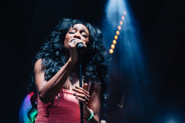 SZA performing at Afropunk Festival in a pink top and voluminous curls 