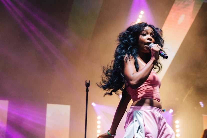 SZA holding a microphone and singing during a concert