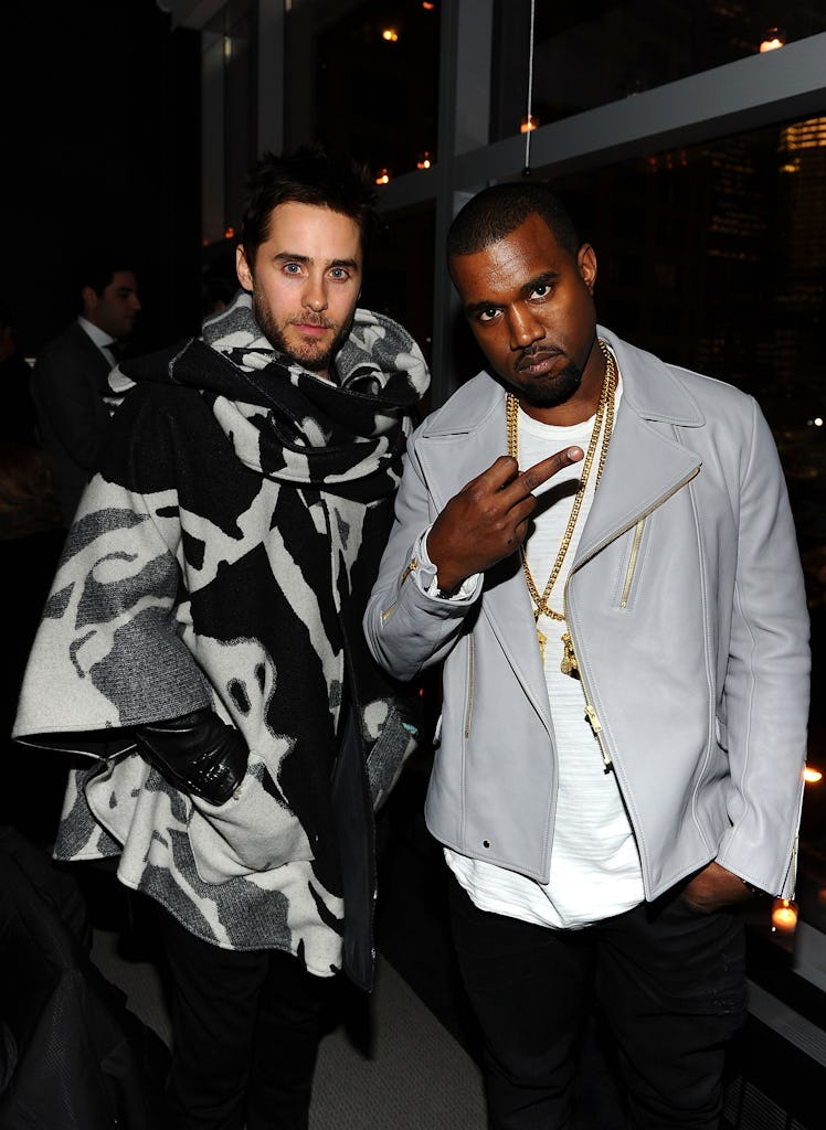 Jared Leto in a black-white-grey poncho posing next to Kanye West in a white shirt and grey jacket