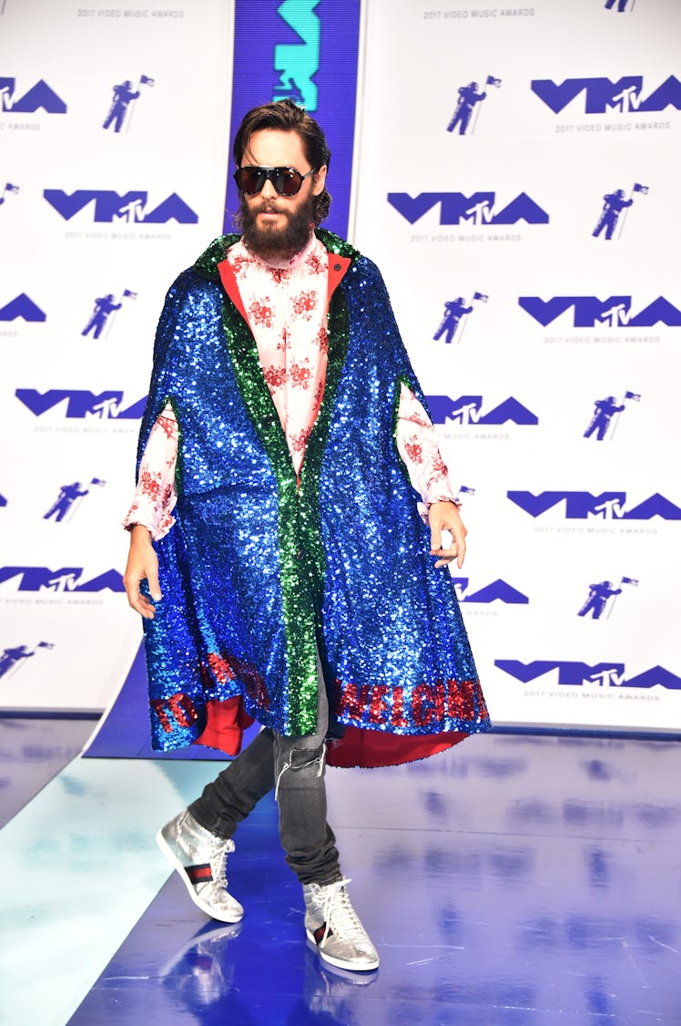 Jared Leto in a white-red floral shirt, a blue-green-red sequin poncho, black denim jeans and sneake...