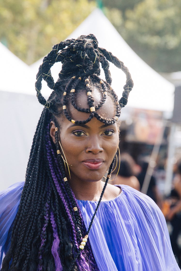 A woman with dreadlocks and beads in her hair wearing a blue dress at Afropunk Festival 