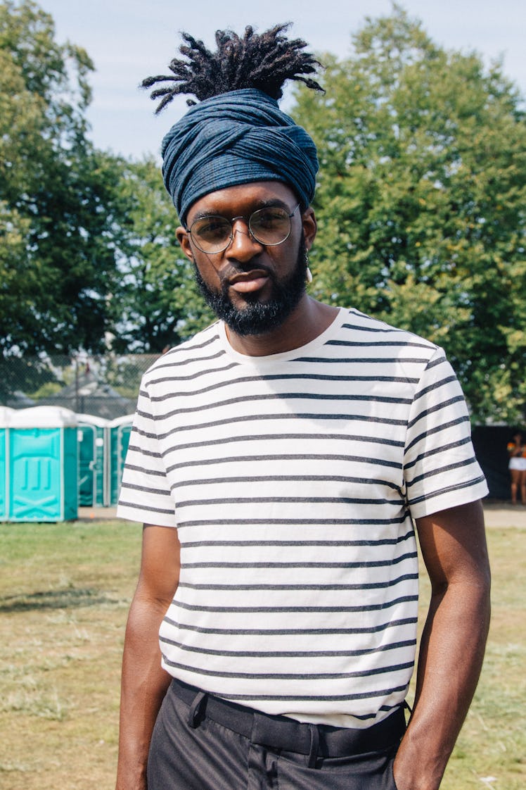 A man with a dreadlock ponytail, a blue headpiece and striped t-shirt at Afropunk Festival