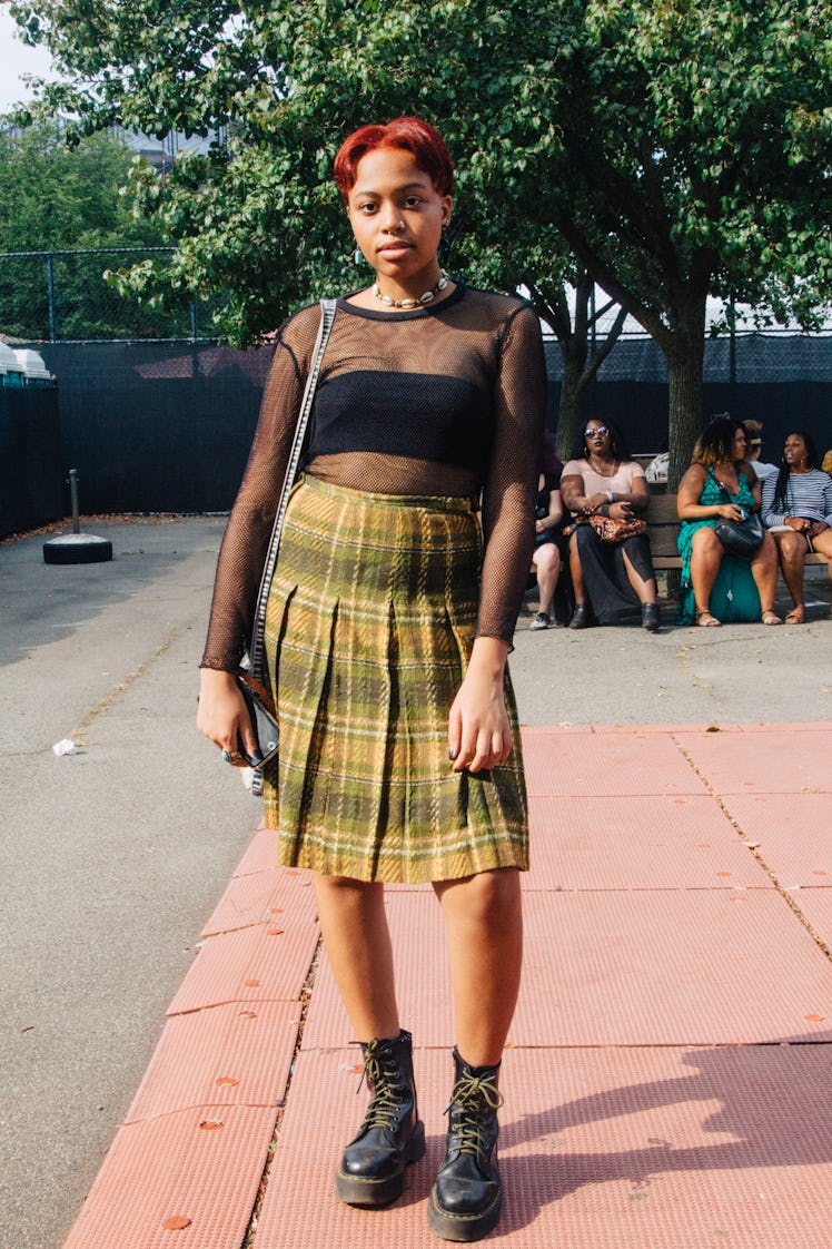 A woman in a black sheer top and yellow plaid skirt at Afropunk Festival