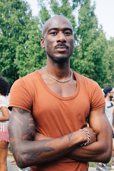 A man in an orange t-shirt and silver chunky jewelry at Afropunk Festival 