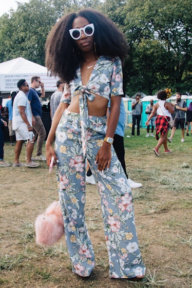 A woman with a long afro wearing a floral top and matching pants 