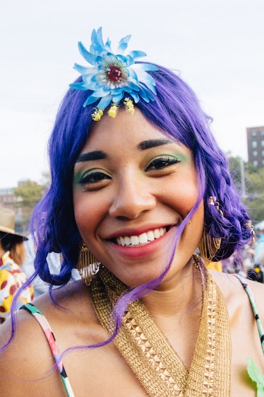 A woman at Afropunk Festival with purple hair and a blue flower as an accessory 