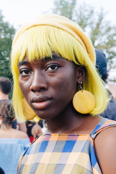 A woman wearing a yellow wig and yellow earrings with a plaid dress at Afropunk Festival 