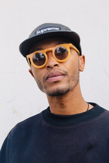A man wearing a Supreme snapback and orange sunglasses posing for a photo at Afropunk Festival 