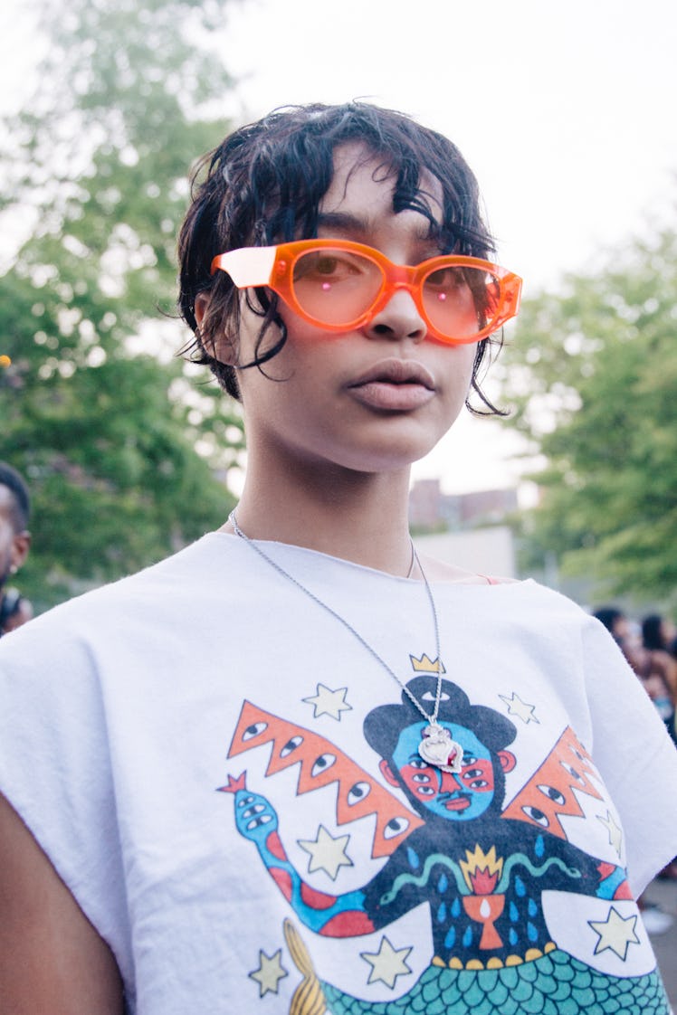 An attendee of Afropunk Festival in orange sunglasses and a white tee 