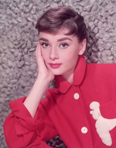 Audrey Hepburn wearing a Pixie cut and a bright red shirt with red lipstick to match