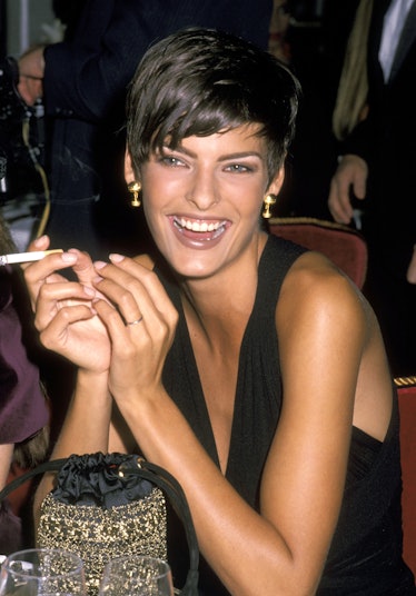  Linda Evangelista smoking a cigarette, smiling, and wearing a Pixie cut