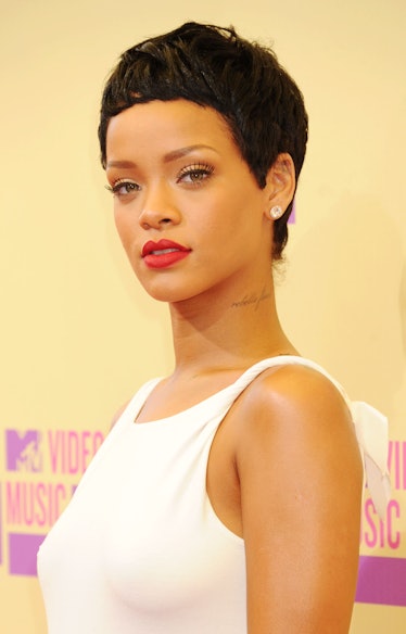 Rihanna wearing a white dress, red lipstick, and her most iconic Pixie cut