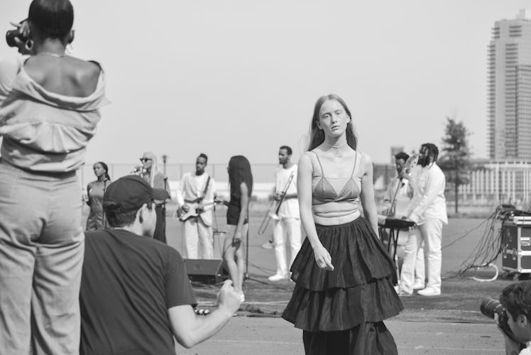 A black and white photo of a model in a long ruffled skirt and a bralette walking off the Maryam Nas...