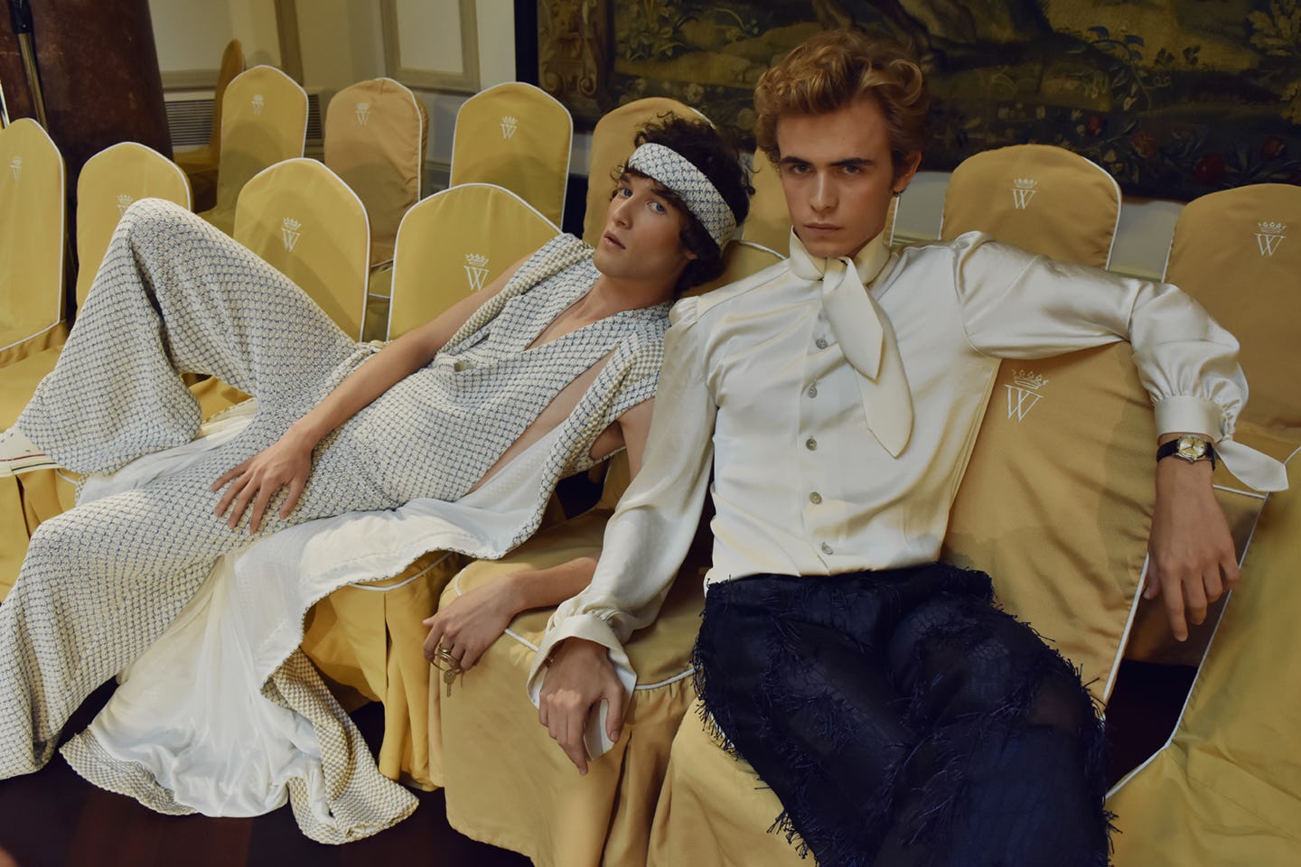 Two male models sitting on chairs while wearing Palomo Spain outfits 