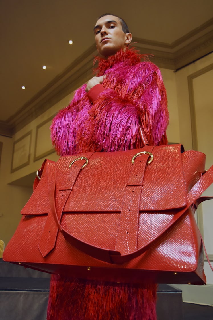 A model in a pink fuzzy fur jacket holding a red leather handbag at Palomo Spain SS18 runway