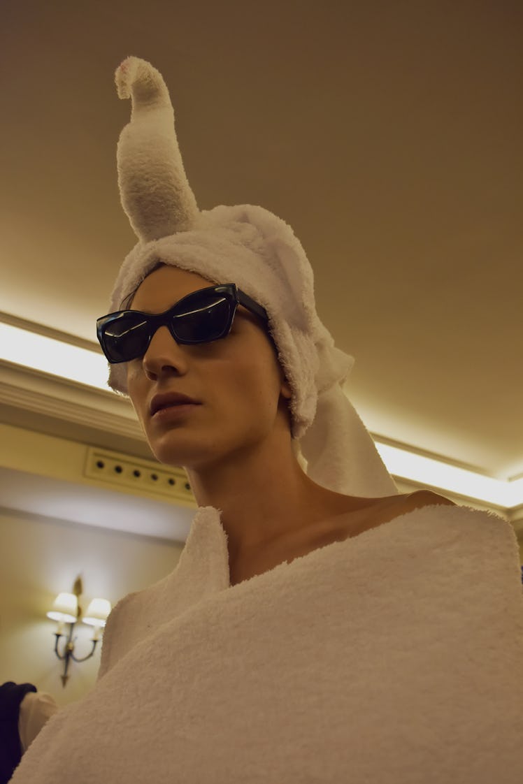 A model wearing a white coat and white swan-shaped headpiece and black sunglasses at the Palomo Spai...