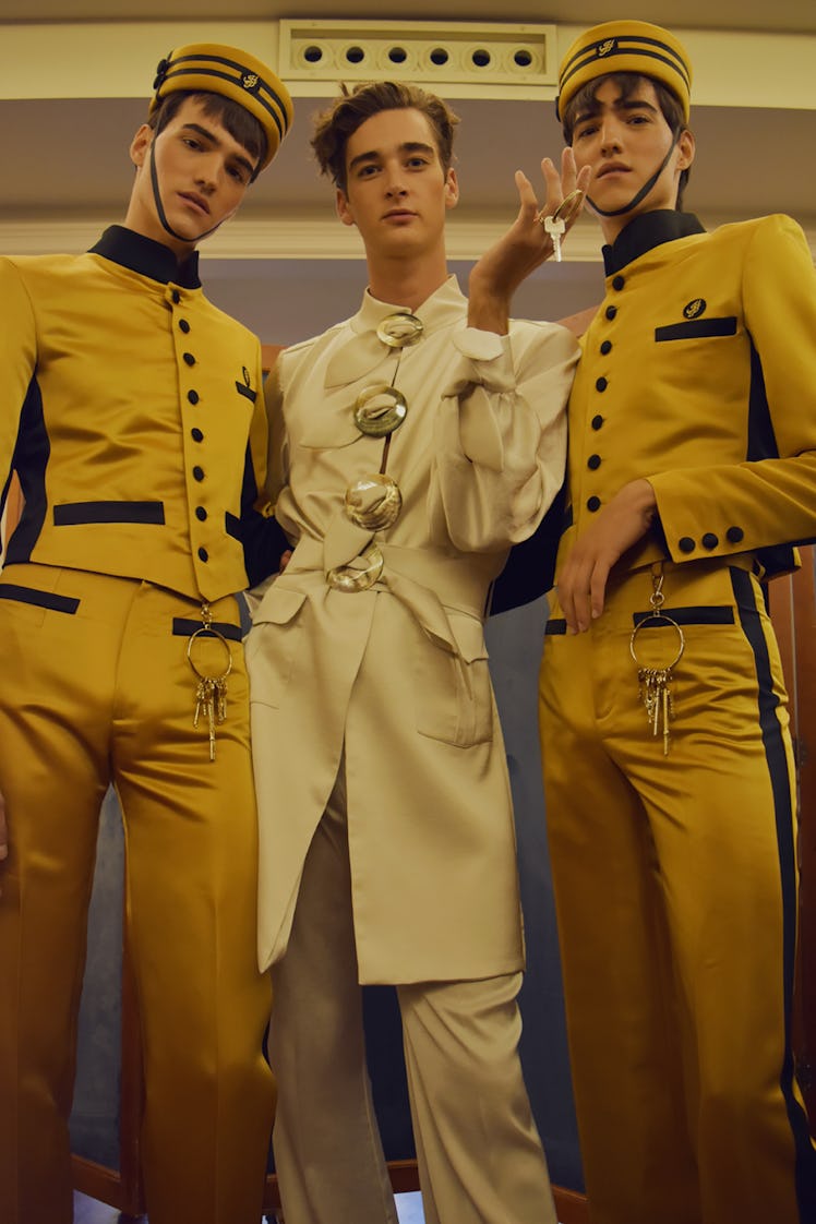 Two models wearing yellow suits and hats and a model wearing a beige coat at the Palomo Spain SS18 r...