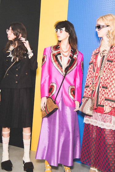 Three models backstage at the Gucci SS18 show in a pink blazer, two-piece set and black blazer with ...