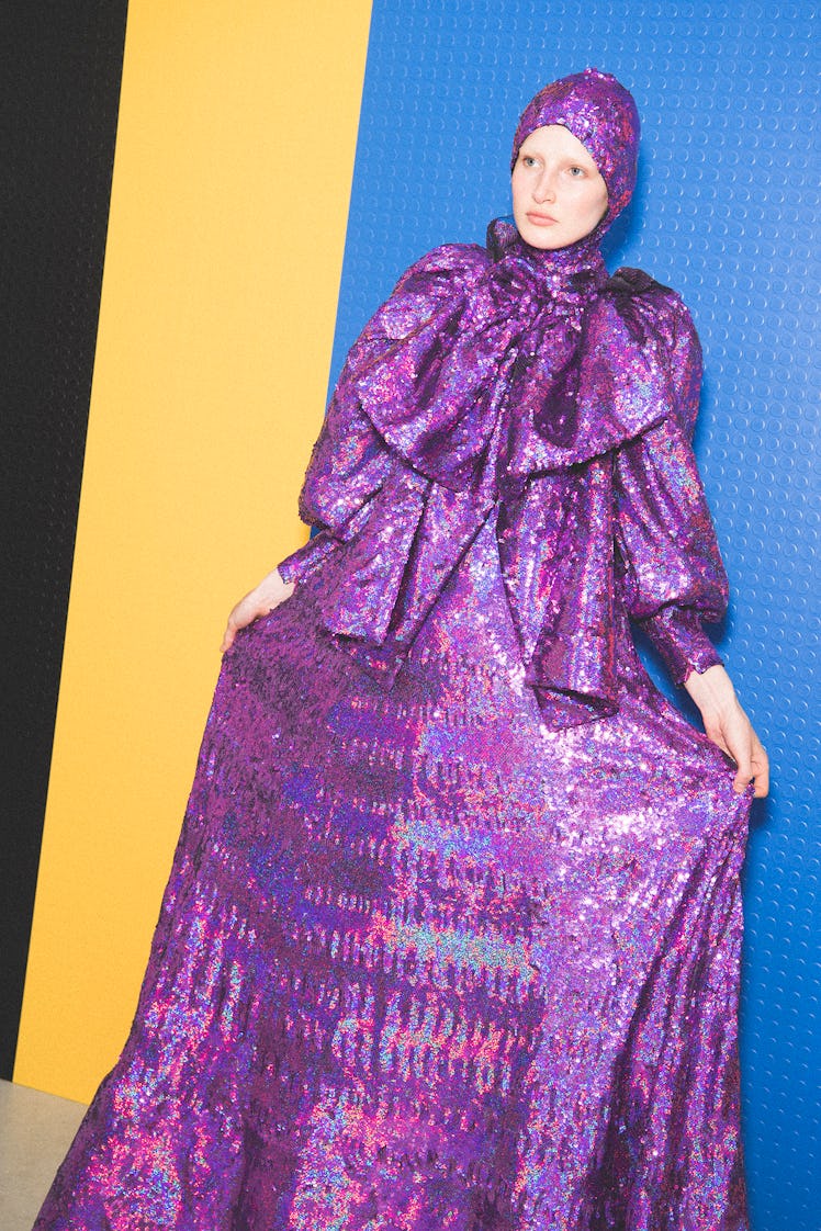 A model posing in a shimmery purple dress that has a matching head piece 