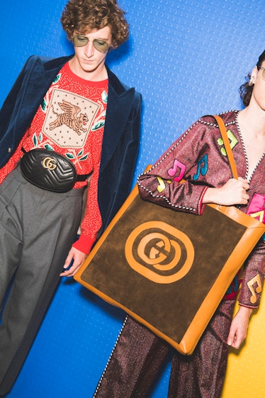 Two models with Gucci bags backstage at the show, one is a tote bag and the other a fanny pack