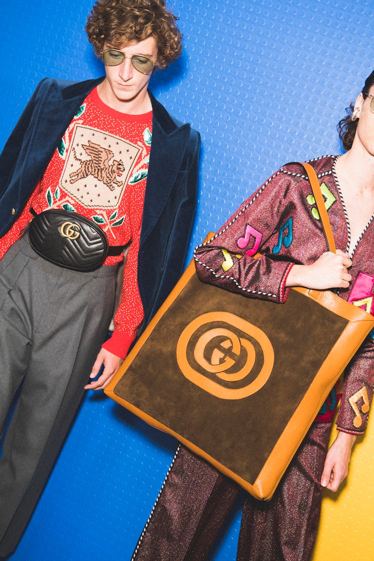 Two models with Gucci bags backstage at the show, one is a tote bag and the other a fanny pack