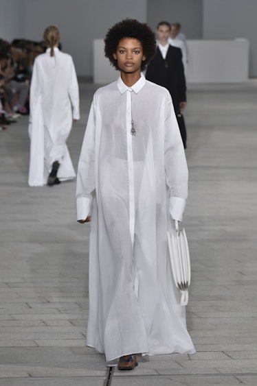A model walking the runway in a long white shirt-dress by Jil Sander at Milan Fashion Week’s Spring ...