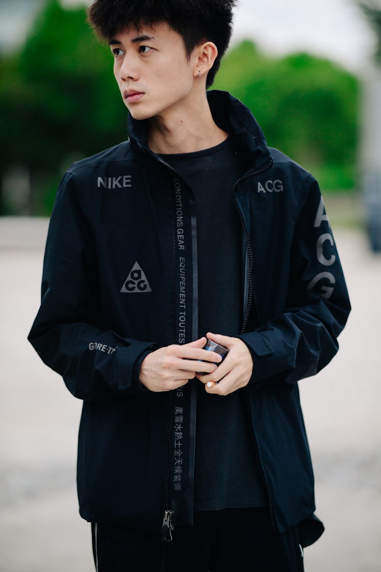 A male model posing while wearing a Nike black jacket 