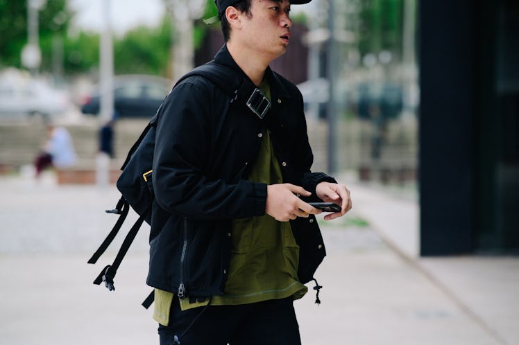 A man walking while wearing a black jacket over a green shirt