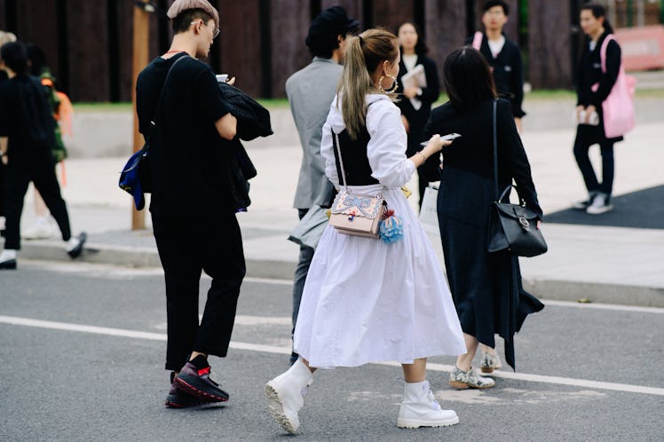 A woman crossing a street while wearing a white dress