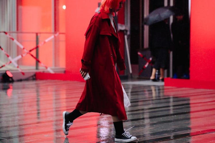 A red-haired woman walking while wearing a red coat