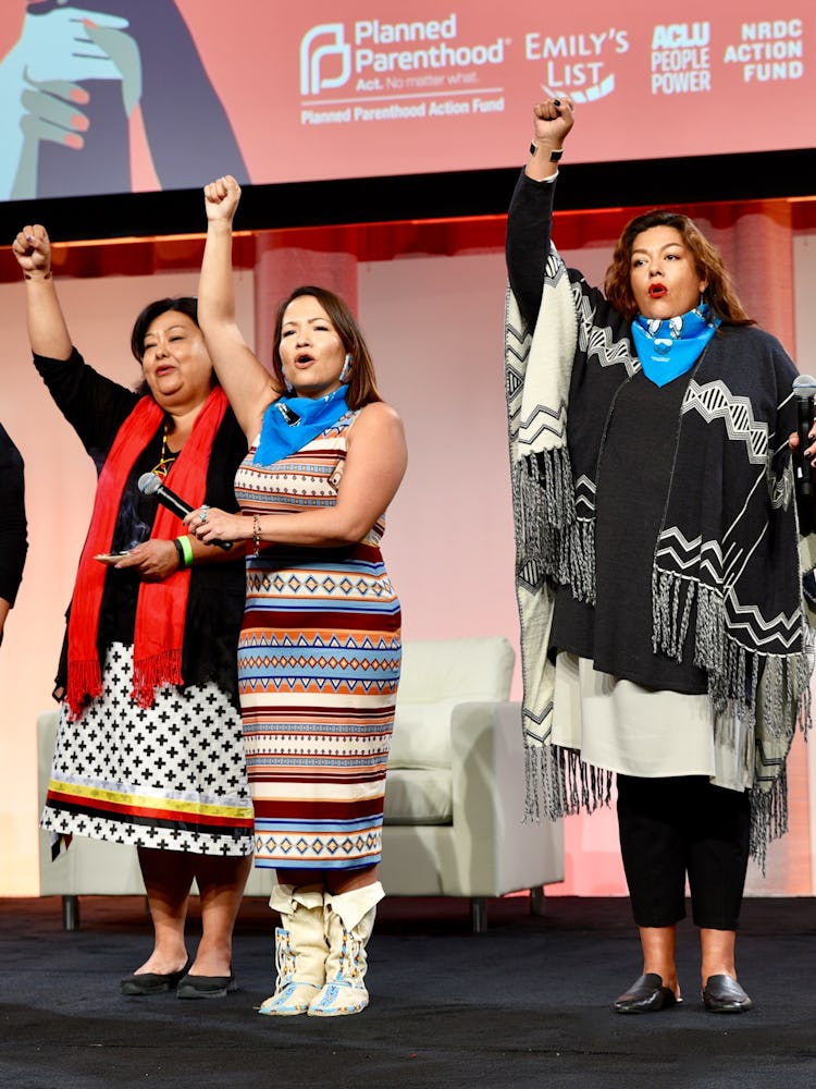 Activists raising hands on stage at the 2017 Women’s Convention, hosted in Detroit, Mich.