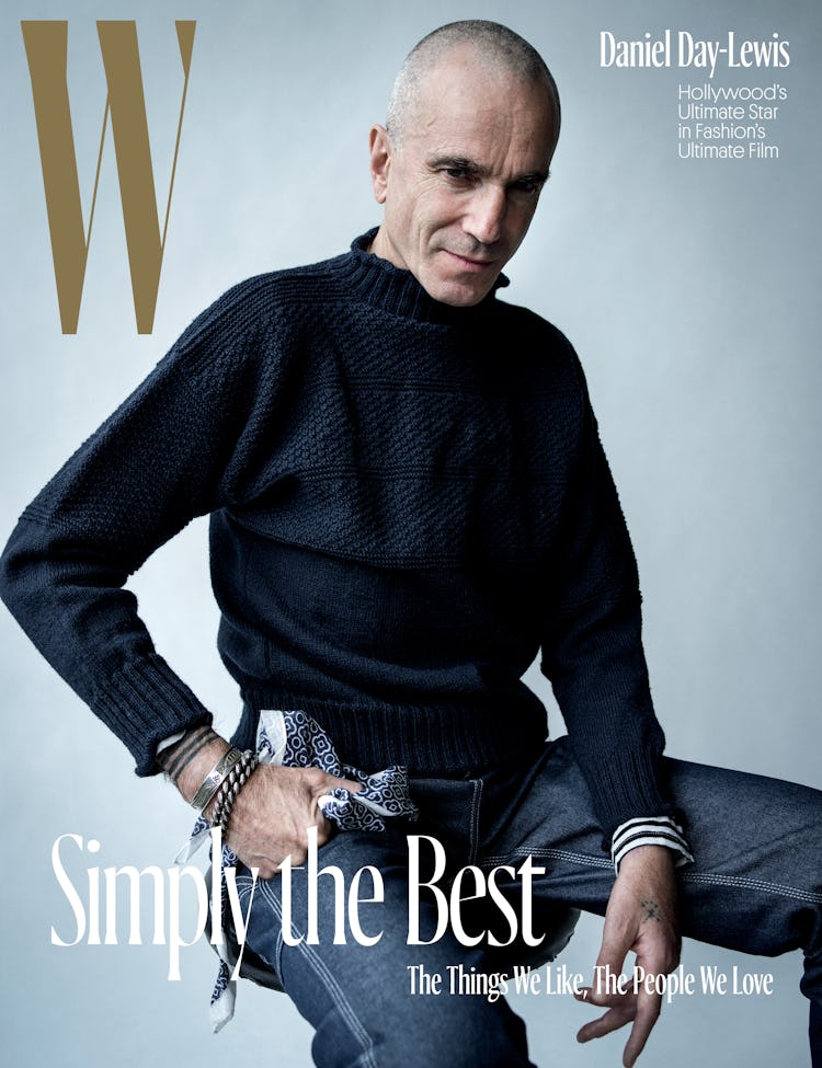 Daniel Day-Lewis sitting in a black sweater and blue denim jeans on the cover of W Magazine