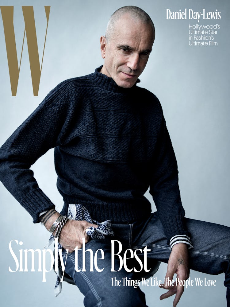 Daniel Day-Lewis sitting in a black sweater and blue denim jeans on the cover of W Magazine