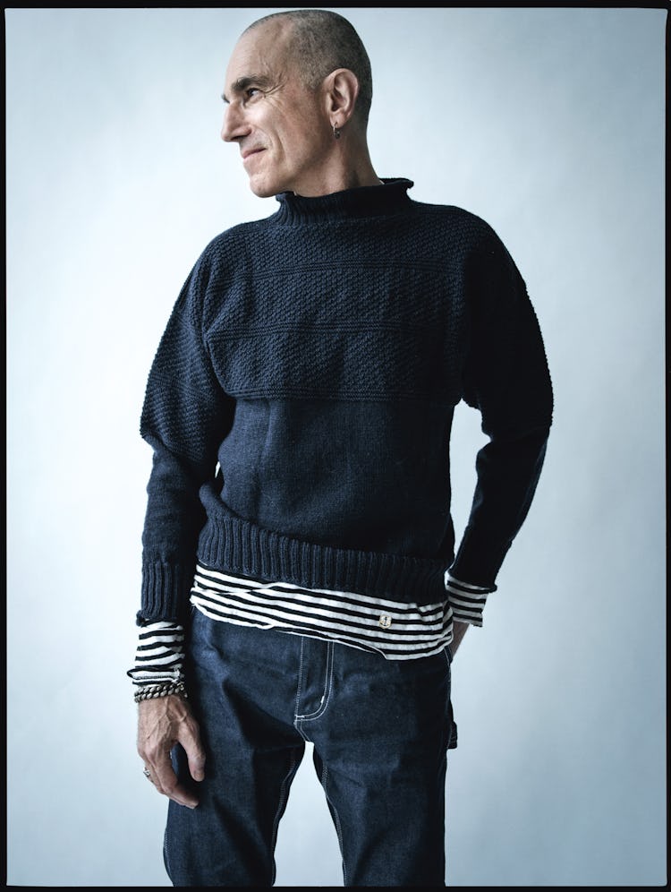 Daniel Day-Lewis standing and posing in a black-white striped shirt, black sweater and blue denim je...