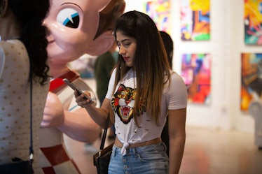 A visitor looking at her phone at Art Basel Miami international art fair