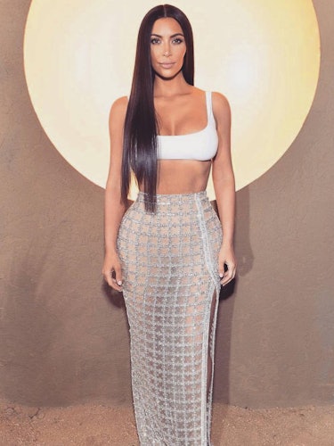 Kim Kardashian in a white bralette and floor-length net skirt with her hair long and straight 