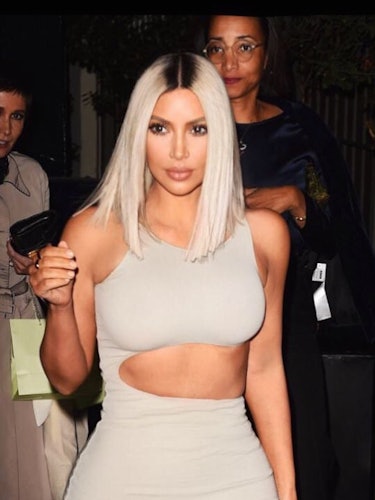 Kim Kardashian in a beige dress with a cutout on the side, with her hair in a platinum blonde should...