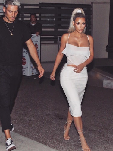 Kim Kardashian in  white top and skirt with her hair in a sleek high ponytail 