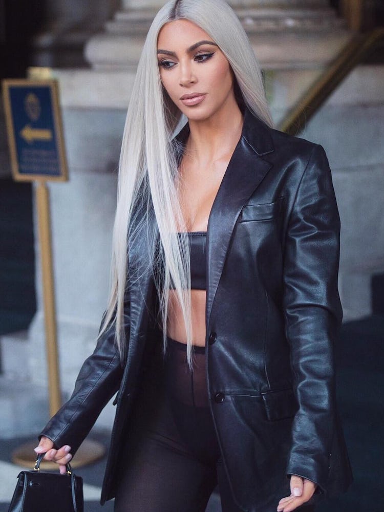 Kim Kardashian in a black top, high-waist leggings and leather jacket with platinum blonde hair 