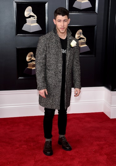 Nick Jonas in a black shirt, a grey tweed coat and black trousers at the Grammys 2018