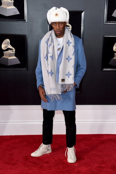 Tyler, The Creator in a blue coat, white-blue scarf, black trousers and a white hat at the Grammys 2...
