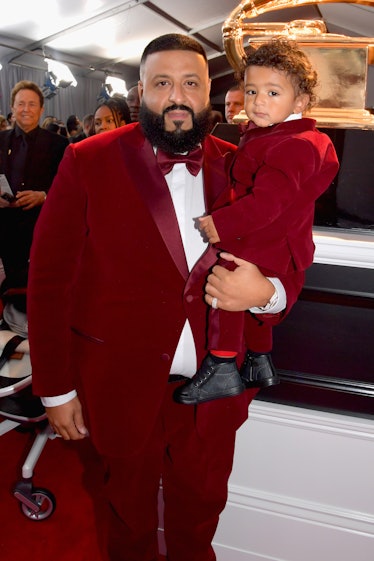 DJ Khaled in a red suit and a white shirt holding his son in a red suit at the Grammys 2018