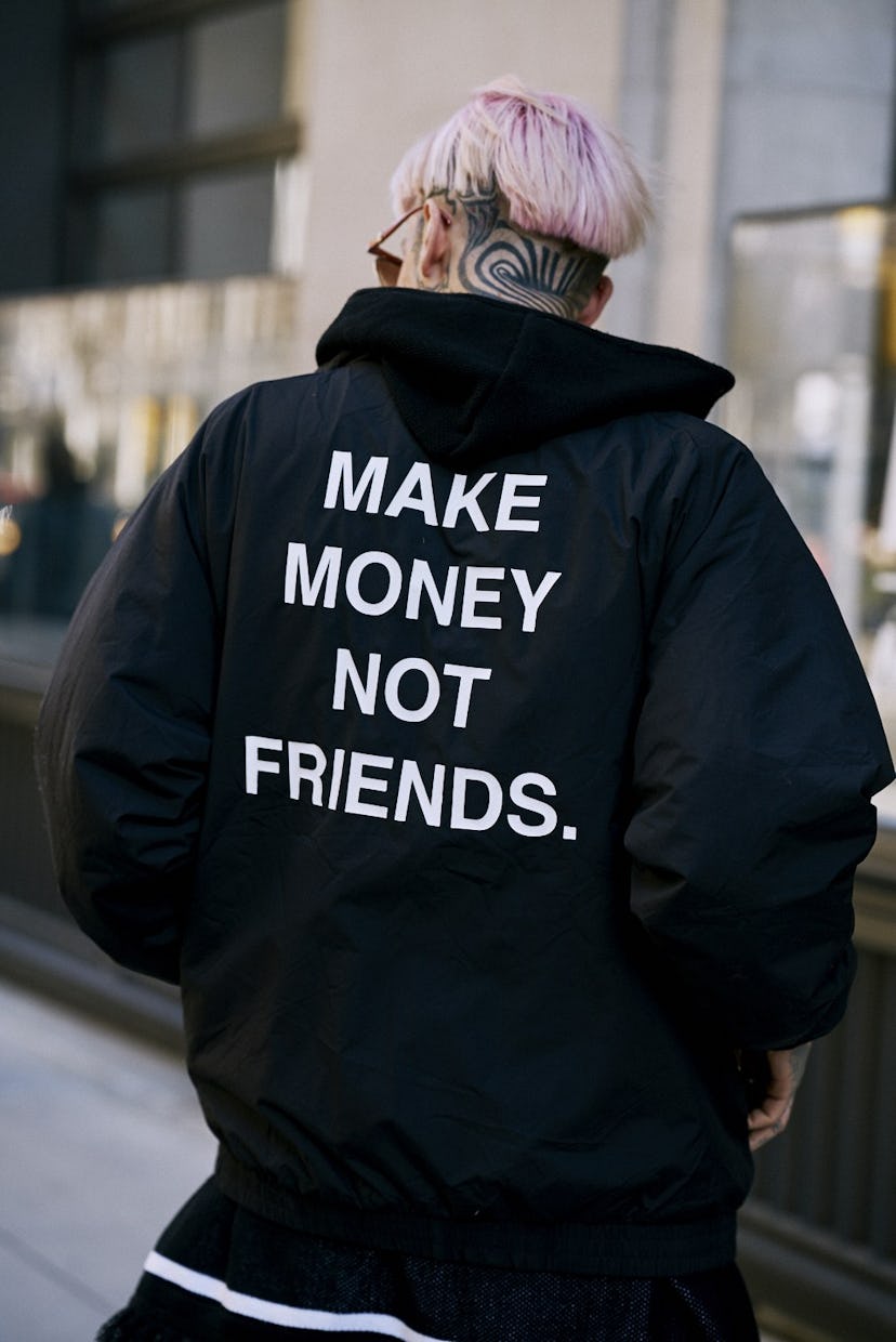 A man from behind with pink hair and a "make money not friends" jacket