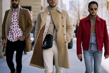 Three men walking in street style coats down a street 