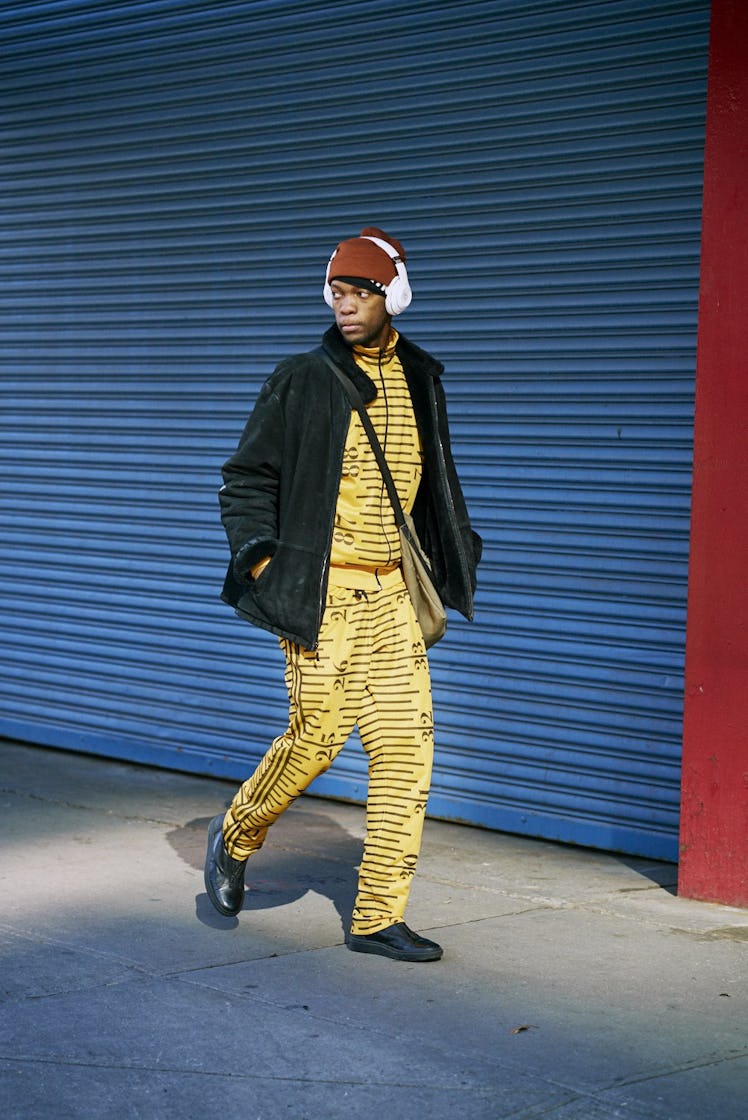 A man walking in a yellow tracksuit and black jacket 