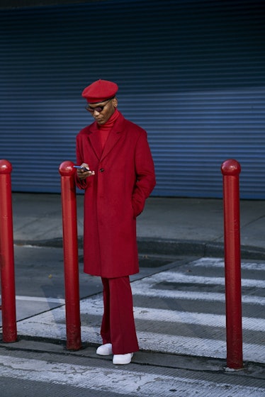 A man wearing a red combination consisted of a coat, sweater, pants, and white sneakers 