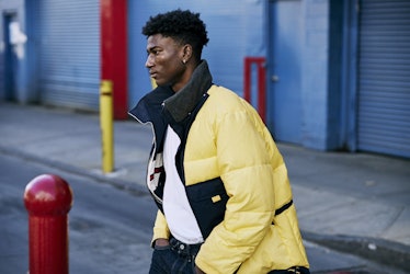 A young man walking in a yellow winter jacket 